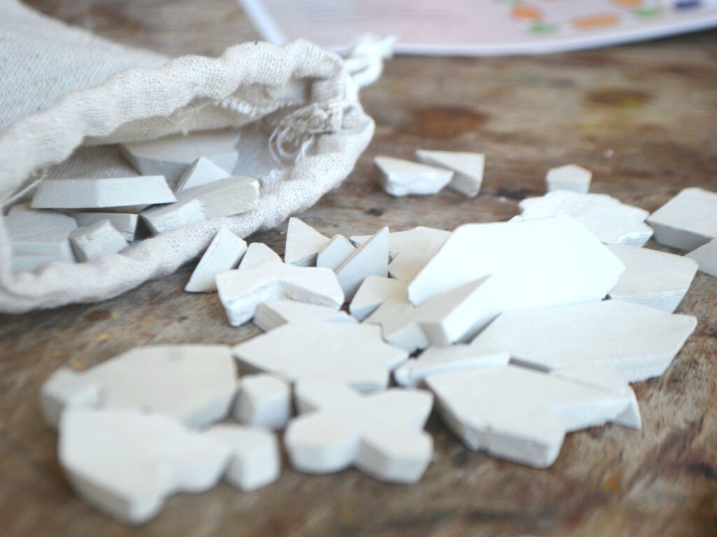 Unpainted clay tiles spilling from a cotton bag