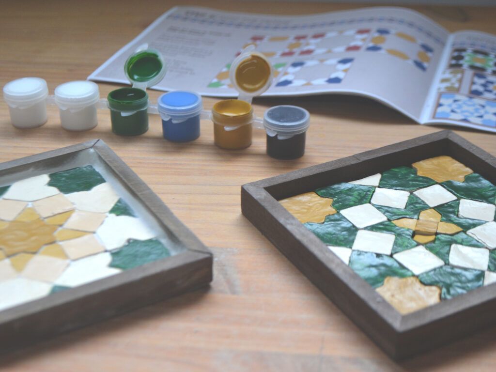 Finished coasters in front of the paint pots and instruction guide